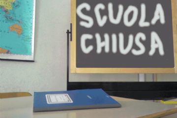 Aula con una cattedra ed un registro blu e una lavagna con la scritta "scuola chiusa"