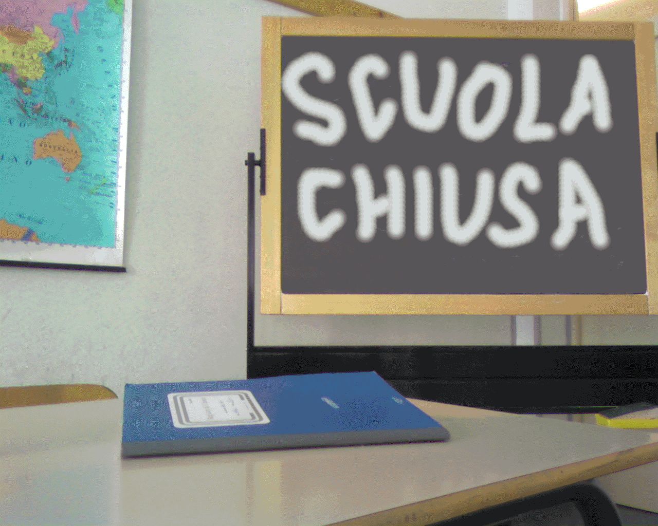 Aula con una cattedra ed un registro blu e una lavagna con la scritta "scuola chiusa"